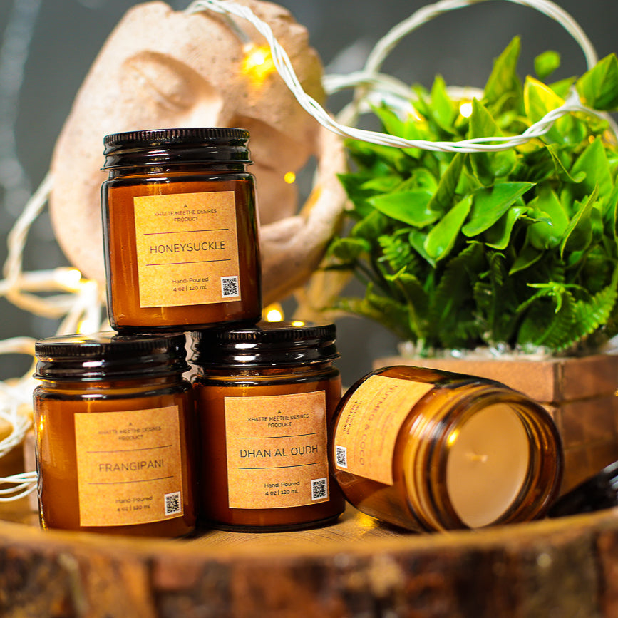 A warm amber-scented candle in a glass jar, casting a golden glow